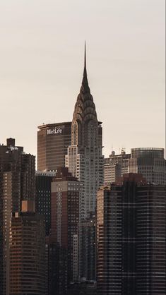 an airplane flying over the top of a large city with tall buildings in the background