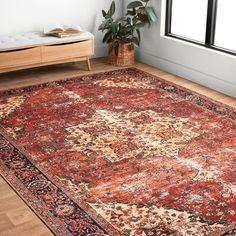 a large red rug with an ornate design on the floor in front of a window