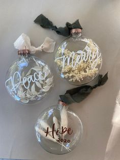 three glass ornaments with the words hope, love and happiness written in white on them