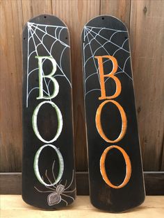 two black snowboards with spider webs and boooo written on the sides, sitting next to each other