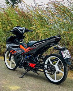 the motorcycle is parked on the side of the road next to tall grass and bushes