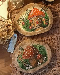 two wooden plates with mushrooms painted on them sitting on top of a doily covered table