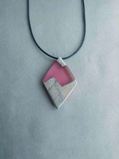 a pink and white square shaped pendant on a black cord necklace with a leather cord