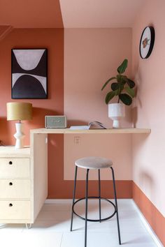 a white stool sitting in front of a desk with a potted plant on it