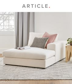 a white couch sitting on top of a wooden floor next to a table and window