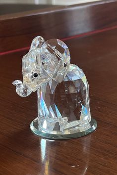 a crystal elephant figurine sitting on top of a wooden table next to a window