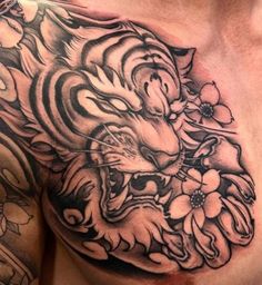 a man's chest with a tiger and flowers tattoo on it, which is black and white