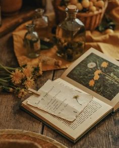 an open book sitting on top of a wooden table next to some yellow flowers and bottles