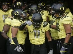 a group of football players standing next to each other wearing black helmets and yellow uniforms