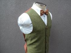 a mannequin wearing a green vest with a brown bow tie and white shirt