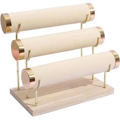 three rolls of toilet paper are on a wooden stand with two metal holders in front of them