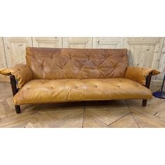 a brown leather couch sitting on top of a hard wood floor