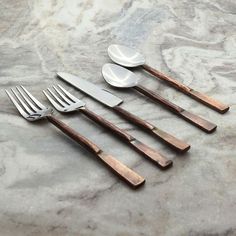 five forks, spoons and two knives on a marble surface