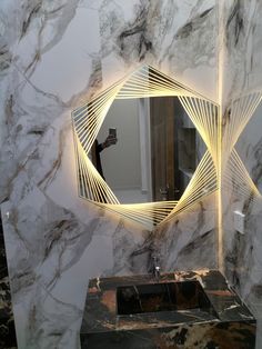 a bathroom with marble walls and a mirror on the wall that has lights in it