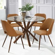 a glass table with six chairs around it in a white dining room area, next to a potted plant