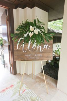 a wooden sign with flowers and greenery on it