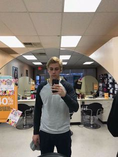 a young man taking a selfie in an office cubicle with his cell phone