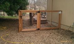 a wooden gate with wire around it in the middle of a dirt area next to a building