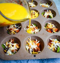 someone pouring orange juice into a muffin tin filled with cupcakes covered in cheese