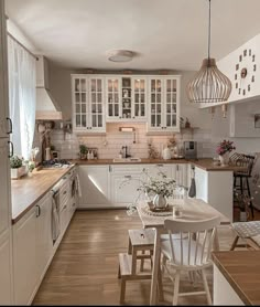 a kitchen filled with lots of white furniture and wooden counter top space next to a dining room table