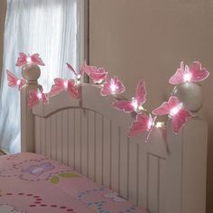 a bed with pink butterflies on the headboard and lights in the shape of flowers