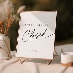 a sign that says sweet table o'clock next to a vase with dried flowers