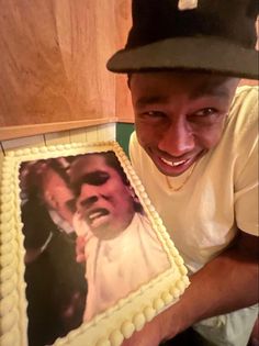 a man holding up a cake with an image of himself on it and smiling at the camera