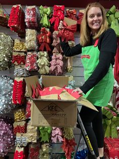 a woman in an apron stands next to a cart full of wrapped presents and bows