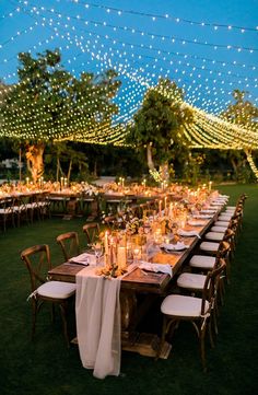 a long table is set up with candles and place settings for an outdoor dinner party