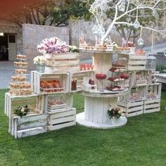 several wooden crates filled with desserts on top of green grass in front of a building