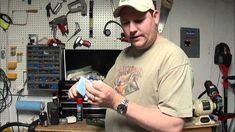 a man holding something in his hands while standing in front of a workbench