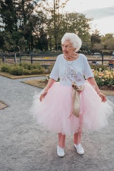 an older woman wearing a pink tutu skirt and t - shirt with the number 90 on it