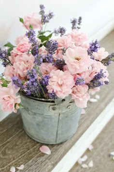 pink and purple flowers are in an old bucket