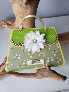 a handbag with a flower on it sitting on a tree branch