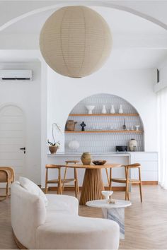 a living room filled with furniture and a round light fixture hanging over the top of a table