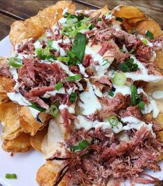 a white plate topped with nachos covered in meat and sour kraut