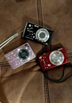 two cameras sitting next to each other on a bed