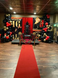 a red carpet is on the floor in front of black and gold balloons