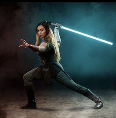 a woman in a star wars outfit is holding a light saber