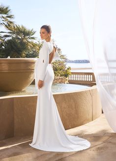 a woman in a white wedding dress standing on a balcony next to a water fountain