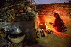 a woman sitting in front of a fire with pots and pans on the ground