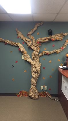 a tree made out of paper on the wall in an office cubicle with decorations