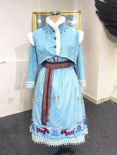 a woman's blue dress with white fur collar and cuffs on display in front of a mirror