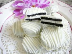 some white chocolates with black stripes on them and a purple flower in the middle