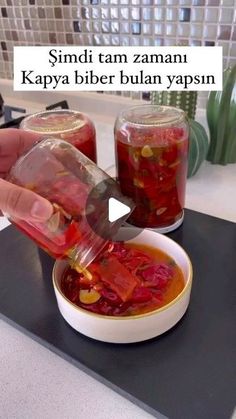 a person is pouring liquid into a bowl with food in it and another hand holding a plastic container