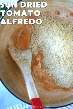 sun dried tomato alfredo in a skillet with a wooden spoon and parmesan cheese on top