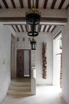 the hallway is lined with white walls and flooring, along with an iron lantern