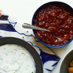 three bowls of food on a table with spoons next to each other and one bowl filled with sauce