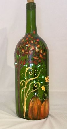 a green glass bottle with autumn decorations on it