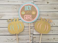 two cake toppers that say boy and girl with gold glitter pumpkins on them